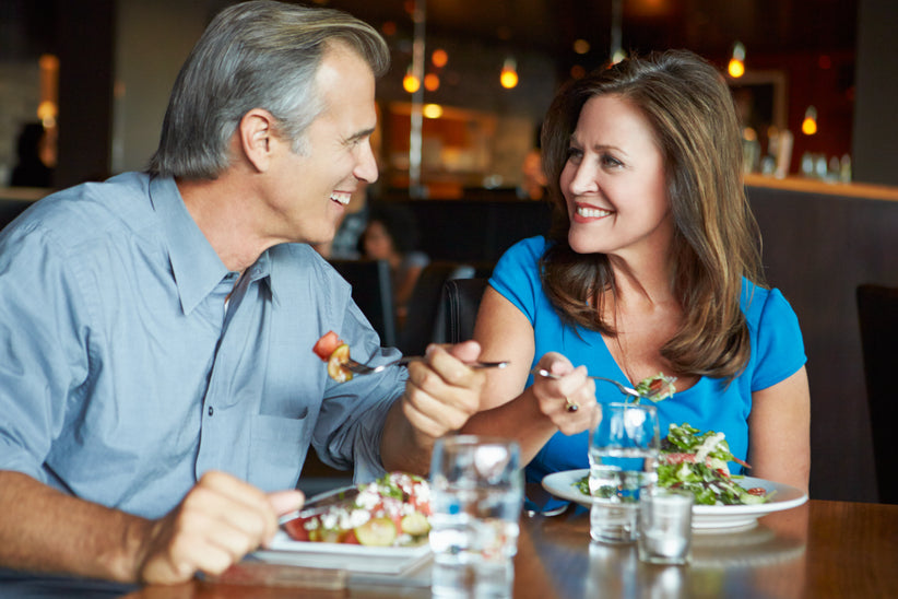 Couple sitting at a restaurant table eating healthy salads