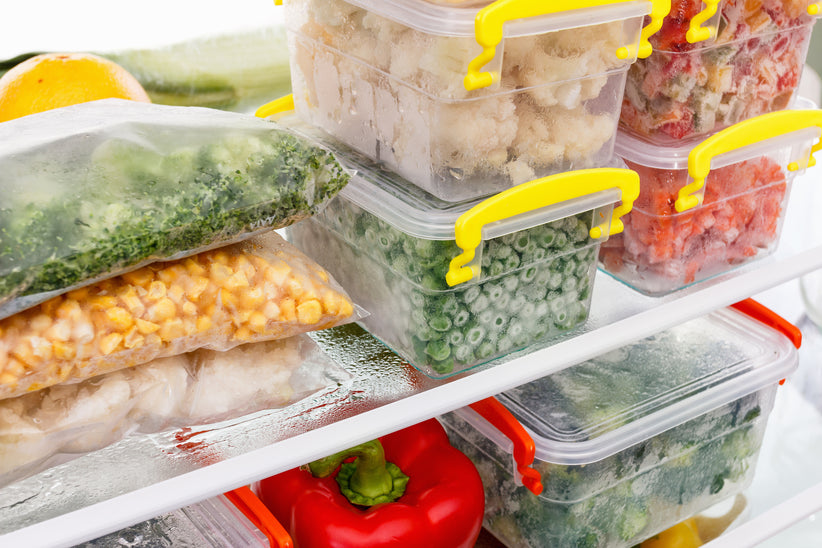 Frozen veggies and other healthy food in containers stacked neatly in a freezer. 