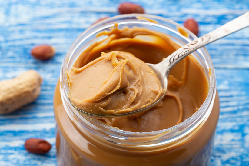 Open jar of peanut butter with a spoon scooping some out