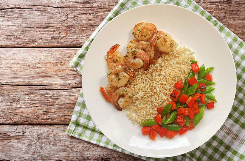 Healthy plate with grilled shrimp, brown rice, and veggies